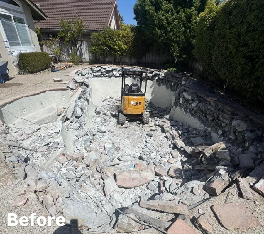 Swimming pool shell broken into rubble with a mini excavator working inside it during a Royal Demolition pool removal