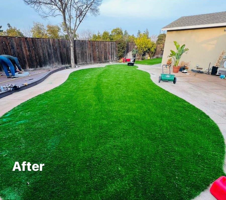 The same backyard after pool removal and backfill, finished with a green artificial turf lawn