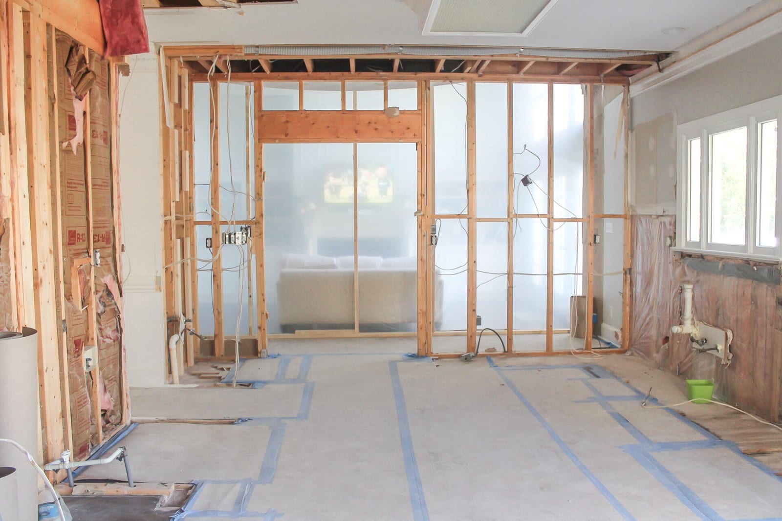Kitchen stripped back to the studs with the floor papered and plastic sheeting sealing off the next room