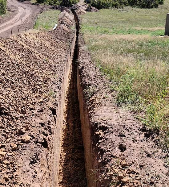 Long straight utility trench with vertical walls and the spoil benched neatly along one side